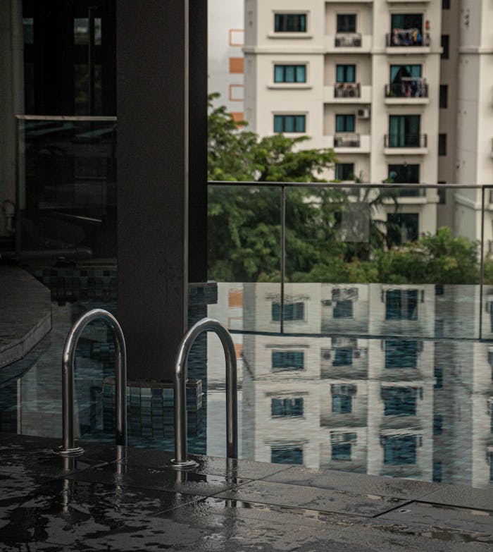 A serene view of a pool with building reflections in an urban setting, emphasizing modern architecture.
